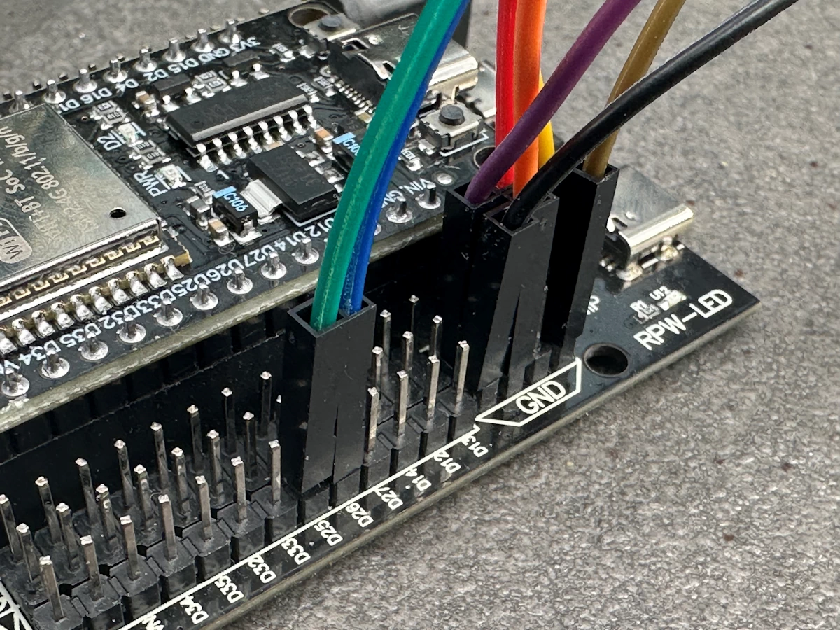 Nahaufnahme der Verkabelung am ESP32 Expansion Board mit grünem Kabel an GPIO25, blauem Kabel an GPIO26 sowie farbigen Leitungen für 3,3 Volt, 5 Volt und Masse
