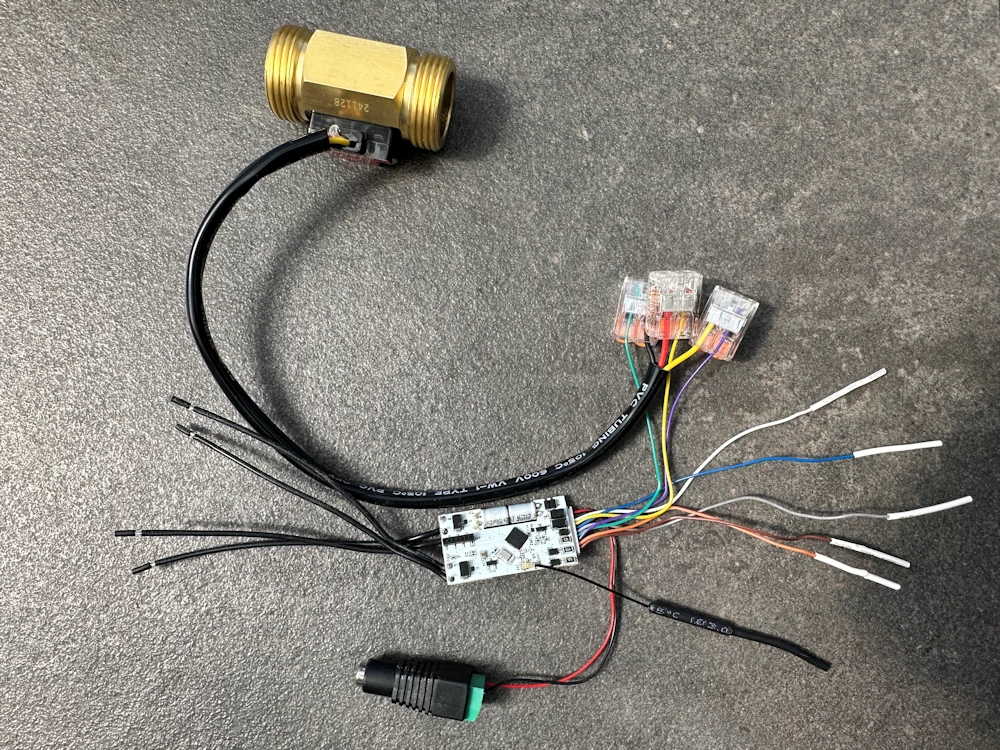 Gesamtübersicht der Verkabelung: Ein Shelly Plus Uni Modul ist über WAGO 221 Klemmen mit einem Wasserdurchfluss-Sensor aus Messing und einem 12V Hohlstecker-Adapter für die Stromversorgung verbunden